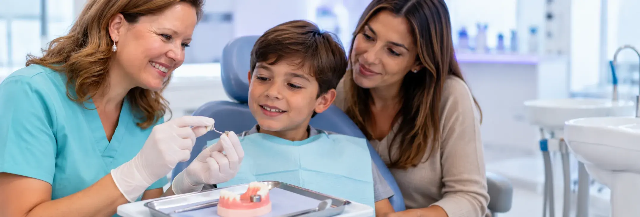 Odontopediatra mostrando un modelo con mantenedor de espacio a un niño en la clínica de Huelva